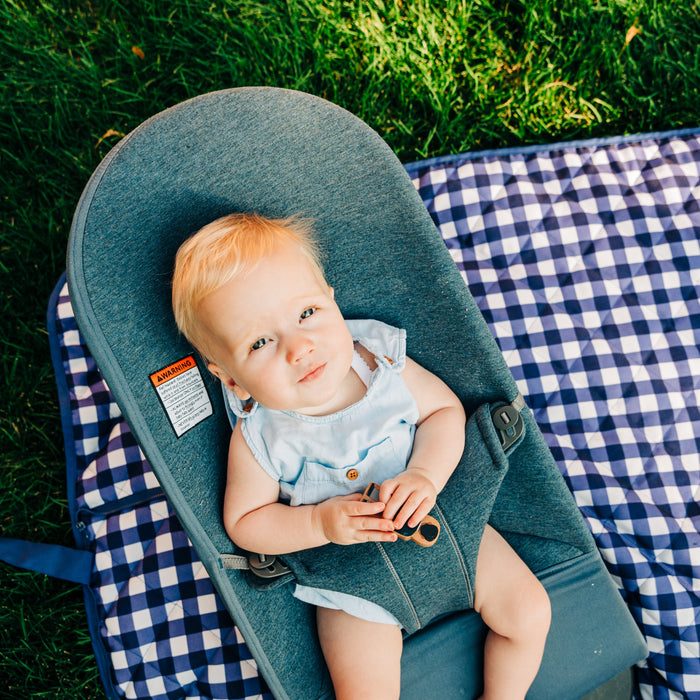 baby sitting in a carrier on a blanket