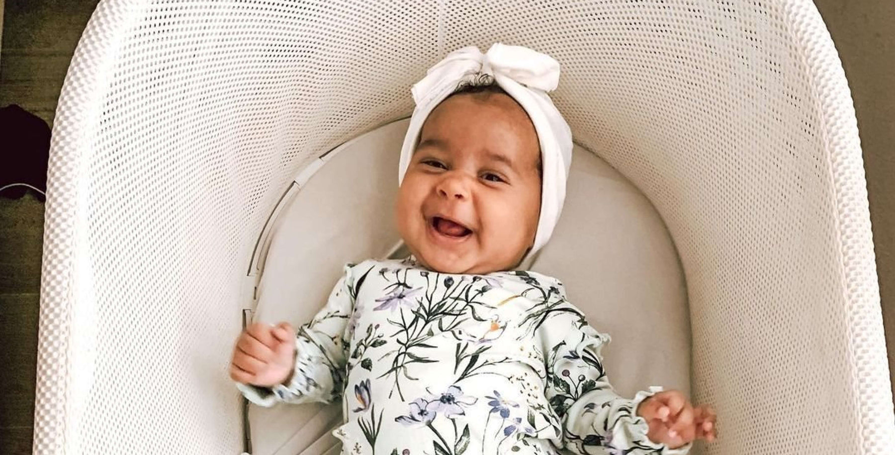 baby smiling while in a bassinet 