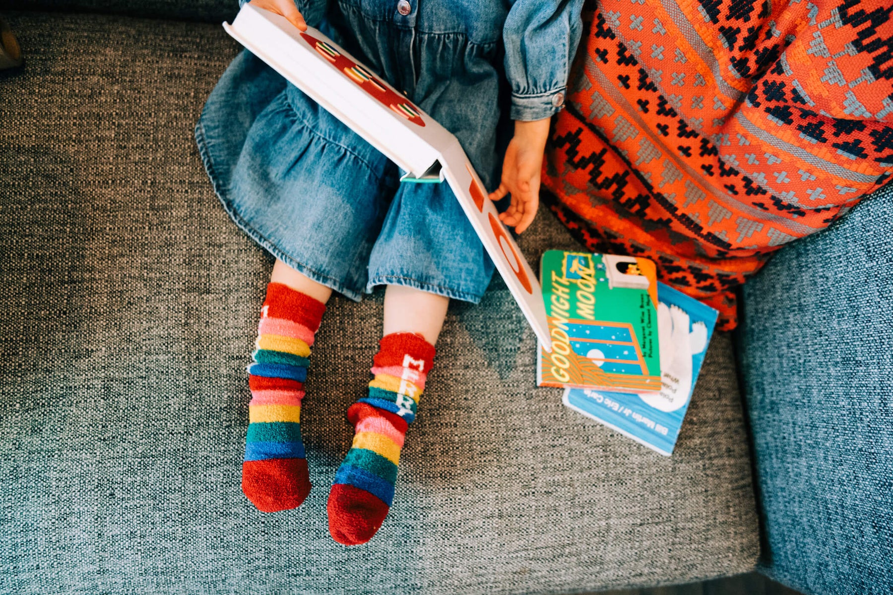 little girl reading a book on the couch in christmas socks