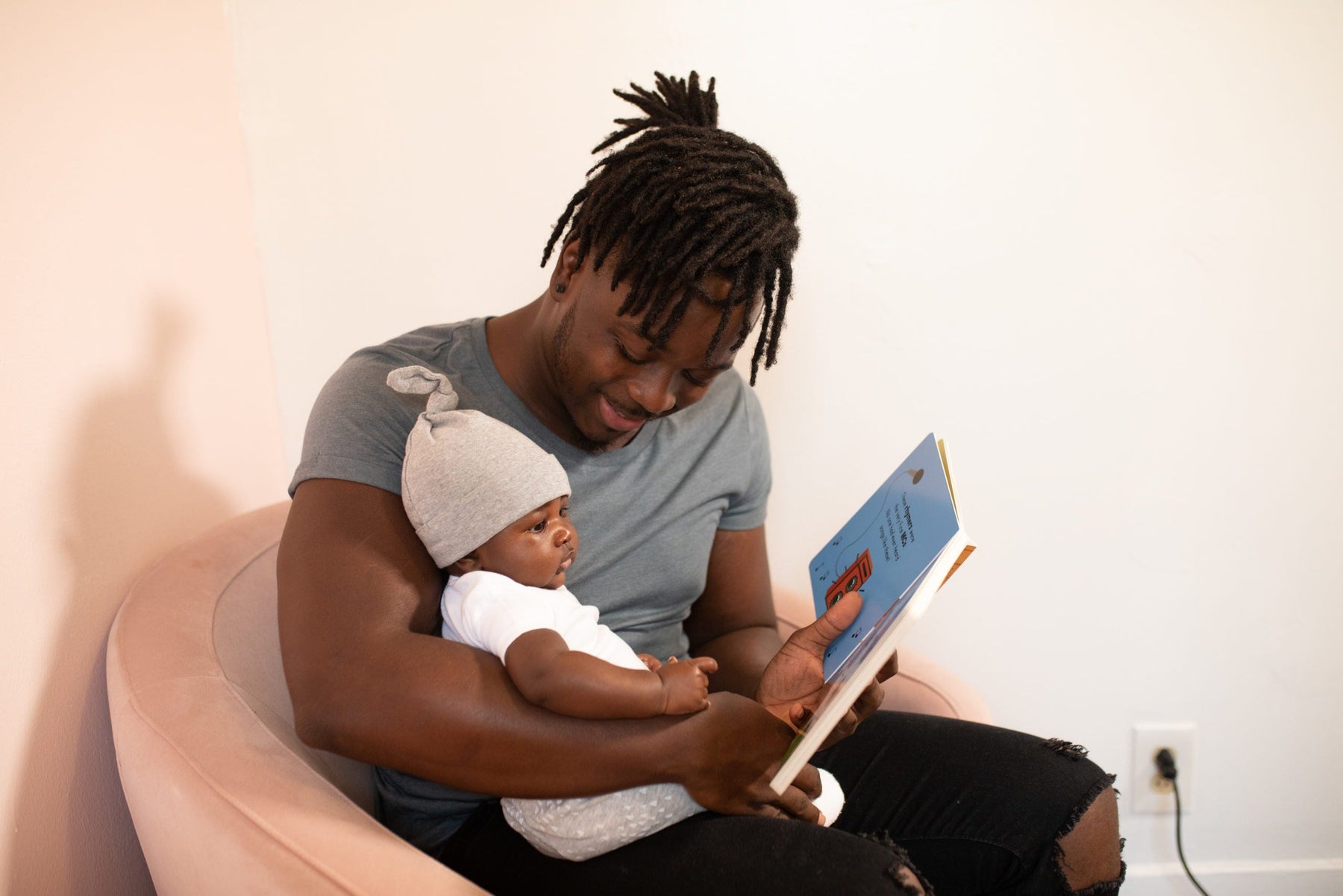 a dad sitting down reading to his baby 