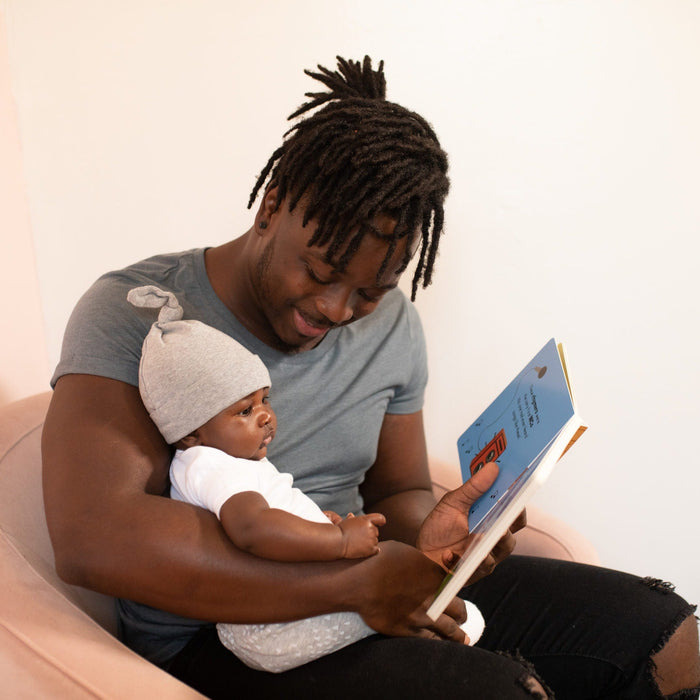 a dad sitting down reading to his baby 