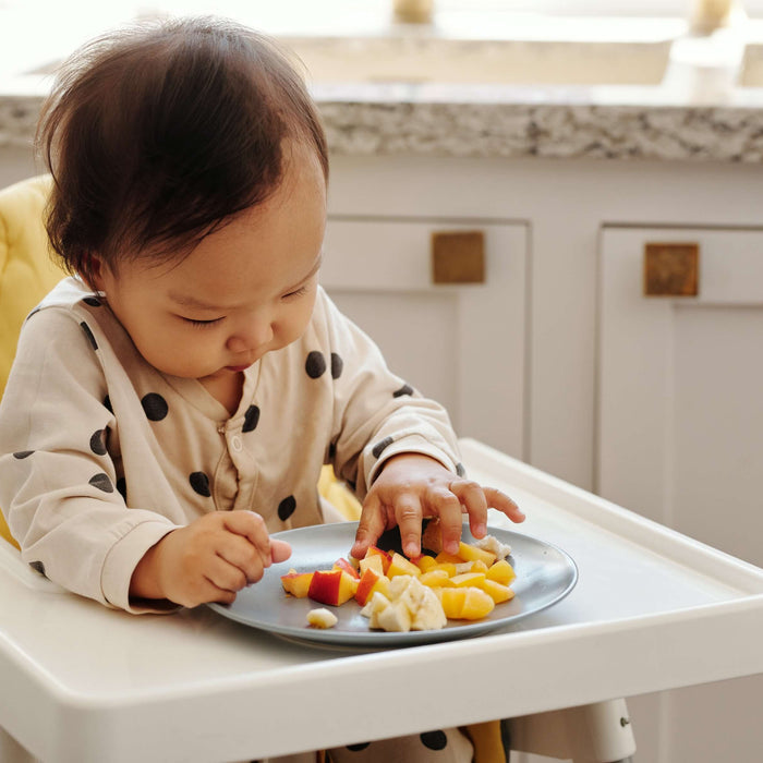 toddler eating in a portable high chair 