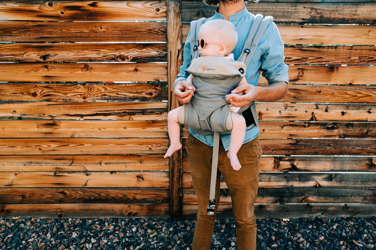 dad holding his baby in a structured carrier 