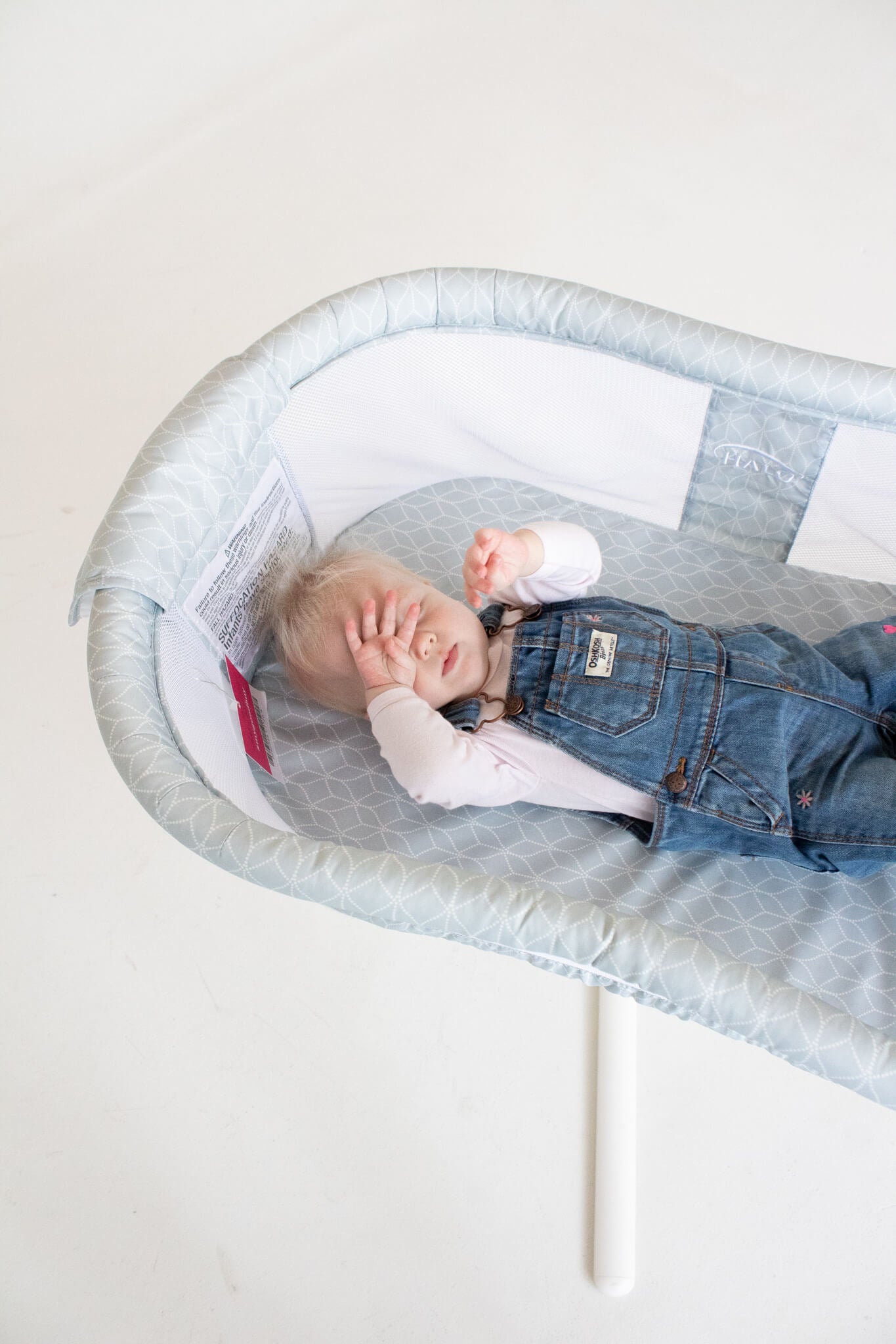 baby sleeping in a tall bassinet