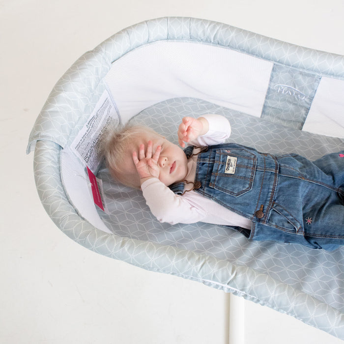 baby sleeping in a tall bassinet