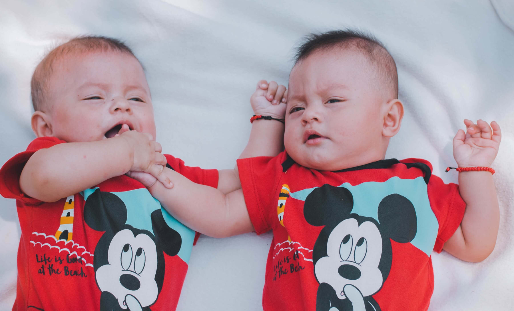 twins sleeping next to each other in matching Mickey Mouse pajamas 